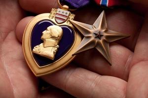 Man Holding Purple Heart and Bronze War Medals photo