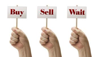 Three Signs In Fists Saying Buy, Sell and Wait photo