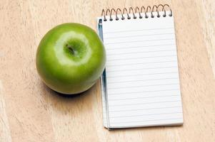 Pad of Paper and Apple on Wood photo