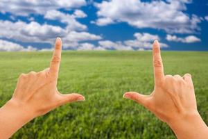 Female Hands Making a Frame Over Grass and Sky photo