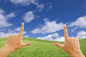 Female Hands Framing Deep Blue Sky Above Grass Field photo