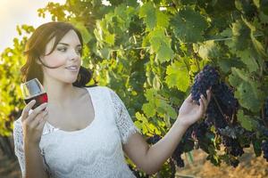 mujer adulta joven disfrutando de una copa de vino en un viñedo foto