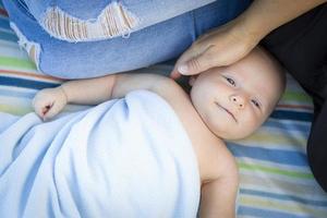 niño pequeño envuelto en su manta descansando con mamá foto