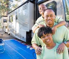 feliz familia afroamericana frente a su hermosa rv en el campamento. foto