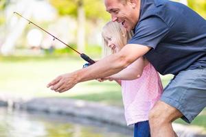 joven caucásico padre e hija divirtiéndose pescando en el lago foto