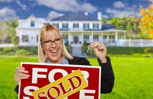 Woman Holding House Keys and Sold Real Estate Sign photo