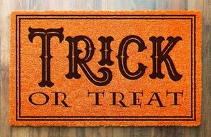 Trick Or Treat Halloween Orange Welcome Mat On Wood Floor Background photo