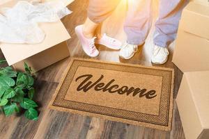 Man and Woman Standing Near Welcome Mat, Moving Boxes and Plant photo