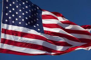 bandera estadounidense ondeando en el viento contra un cielo azul profundo foto