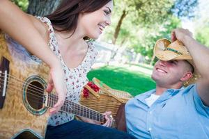 Young Adult Girl Playing Guitar with Boyfriend In The Park. photo