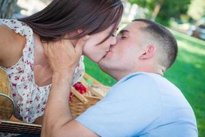 pareja de adultos jóvenes con guitarra besándose en el parque. foto