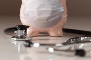 Stethoscope and Piggy Bank Wearing Protective Medical Face Mask. photo