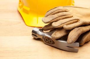 Yellow Hard Hat, Gloves and Hammer on Wood photo