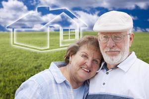 Senior Couple Standing in Grass Field with Ghosted House Behind photo