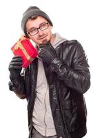 Warmly Dressed Young Man Holding Wrapped Gift To His Ear photo