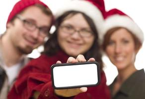 Girl with Friends and Santa Hats Holding Blank Smart Phone photo