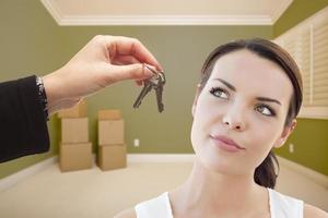 Young Woman Being Handed Keys in Empty Room with Boxes photo