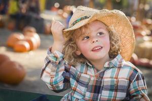 niño pequeño con sombrero de vaquero en el huerto de calabazas foto