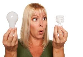 mujer divertida sosteniendo bombillas de bajo consumo y regulares foto