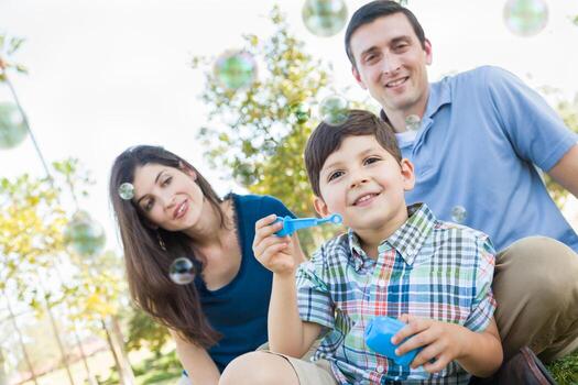 Young Boy Blowing Bubbles with His Parents in the Park. photo