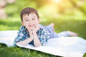 Mixed Race Chinese and Caucasian Young Boy Relaxing Outside On The Grass photo