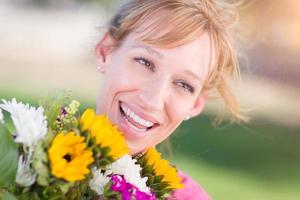 Outdoor Portrait of an Excited Young Adult Brown Eyed Woman Holding a Bouquet of Flowers. photo