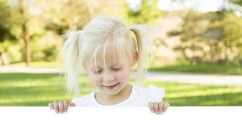 linda niña sosteniendo una pizarra blanca con espacio para texto foto