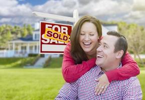 Couple In Front of Sold For Sale Sign and House photo