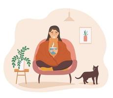 The girl is sitting on the armchair with a cup of hot drink under the blanket. A woman is warming herself under a blanket with a pet cat next to her. Vector graphics.