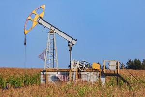 The old oil pump in a field under blue sky photo