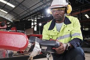 An African American production engineer test and control robotic arm in mechanical manufacturing factory, intelligent automatic machines in industrial business, and futuristic technology innovation. photo