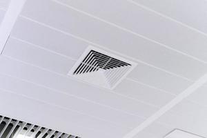 aire acondicionado tipo casete montado en el techo y luz de lámpara moderna en el techo blanco. aire acondicionado por conductos para casa u oficina foto
