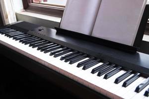 Electric piano with empty sheet music near the window close up view from right angle photo