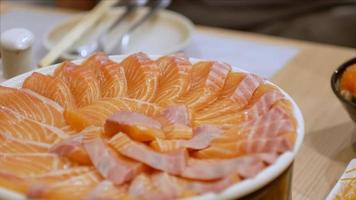 Video de 4k del uso de chopctick pick slamon de un plato lleno de sashimi de salmón