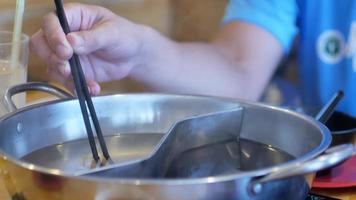 Blick auf den Shabut Hot Pot, während man Schweinefleisch in den Topf legt video