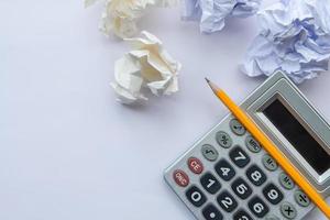 Top view of crumpled paper, yellow pencil, calculator on white table. For brainstorming, work hard, stress concept photo