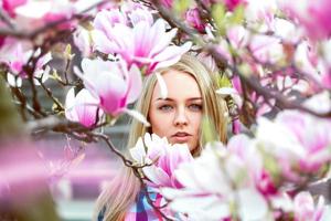 dama rubia de alta sociedad en flores rosadas mirando a la cámara foto