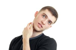 handsome young guy with a beard tilted his head and keeps a hand near the neck is isolated on a white background photo