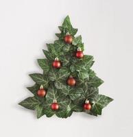 Christmas tree made of an ivy leaves, and decorated with red Christmas bulbs. White background. Evergreen flat lay. photo