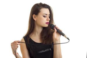 chica sensual con los ojos cerrados cantando karaoke en el micrófono foto