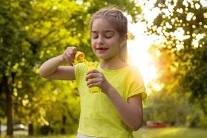joyful little girl standing with soap bubbles in the hands of close-up photo