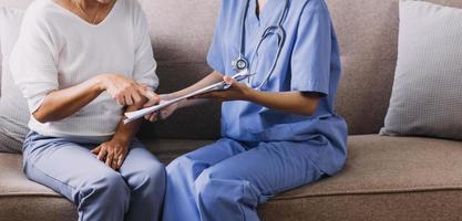 Homecare nursing service and elderly people cardiology healthcare. Close up of young hispanic female doctor nurse check mature caucasian man patient heartbeat using stethoscope during visit photo