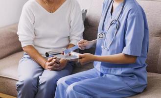 Homecare nursing service and elderly people cardiology healthcare. Close up of young hispanic female doctor nurse check mature caucasian man patient heartbeat using stethoscope during visit photo