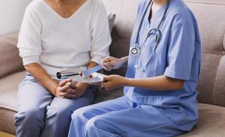 Homecare nursing service and elderly people cardiology healthcare. Close up of young hispanic female doctor nurse check mature caucasian man patient heartbeat using stethoscope during visit photo