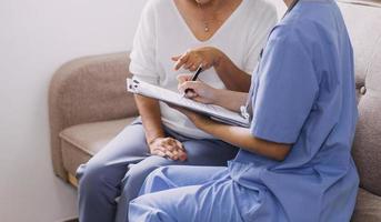 Homecare nursing service and elderly people cardiology healthcare. Close up of young hispanic female doctor nurse check mature caucasian man patient heartbeat using stethoscope during visit photo