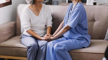 Homecare nursing service and elderly people cardiology healthcare. Close up of young hispanic female doctor nurse check mature caucasian man patient heartbeat using stethoscope during visit photo