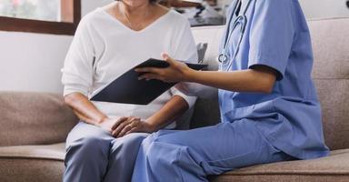 Homecare nursing service and elderly people cardiology healthcare. Close up of young hispanic female doctor nurse check mature caucasian man patient heartbeat using stethoscope during visit photo