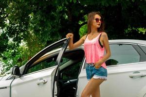 attractive fashion Lady in glasses and short shorts opens the car door photo