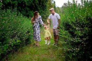 Happy young parents playing with their little baby girl at the green garden photo