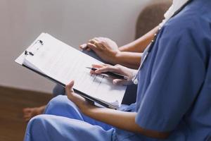 Homecare nursing service and elderly people cardiology healthcare. Close up of young hispanic female doctor nurse check mature caucasian man patient heartbeat using stethoscope during visit photo